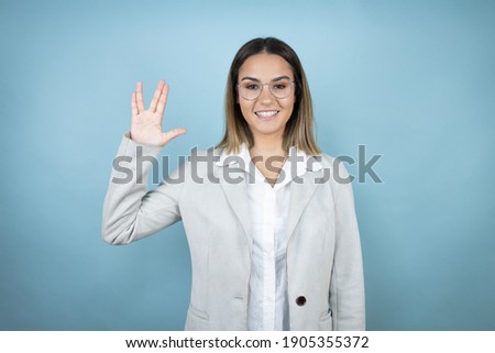 Young business woman over isolated blue background doing hand symbol