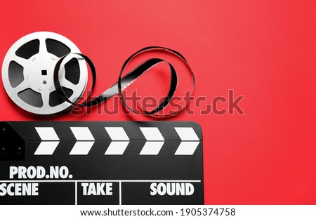 Clapboard and reel on red background, flat lay with space for text. Video production equipment