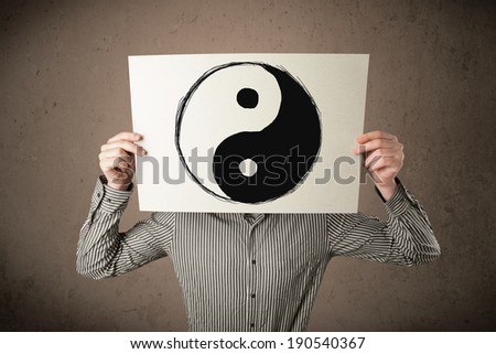 Businessman holding a paper with a yin-yang symbol on it in front of his head