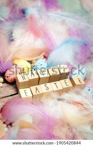 Happy Easter written with wooden cubes surrounded with beautiful pastel colored decorative feathers and eggs, April, Easter, Religion, Spring concept for background and greeting card top 