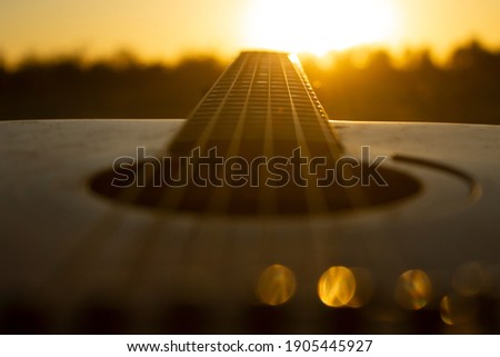 Acoustic guitar with the sunset.The guitar's chords were chosen to be the leading lines that lead people's eyes straight to the sunset. Royalty-Free Stock Photo #1905445927