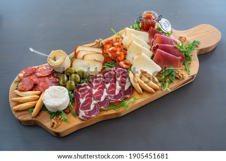 Very colorful tapas board of charcuterie with cheese and smoked meats. Decorated with arugula and walnuts. Royalty-Free Stock Photo #1905451681