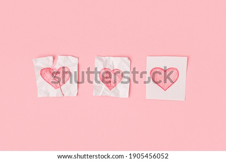 Three hearts drawn on pieces of paper on a pink background. One heart is torn, the second is crumpled, the third is whole. Progress of love.