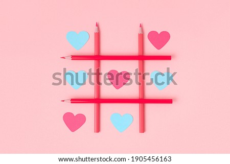 Tic-tac-toe with paper-cut hearts on a pink background. Different love of all colors. Blue and pink hearts.