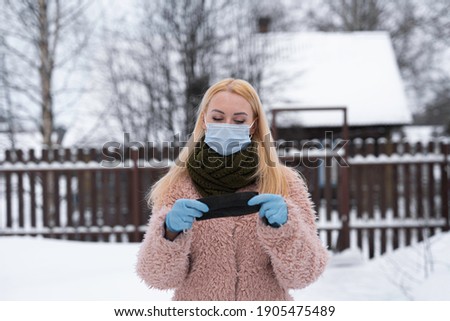 young girl, with a blue medical mask on her face, holds in her hands, in blue gloves, a second mask.