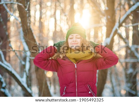 Winter portrait of young beautiful brunette woman wearing yellow snood in snow. Snowing winter beauty fashion concept.