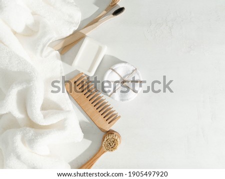 Various eco frendly items - toothbrushes, hairbrush, reusable cotton pads white towel and facial brush on white background. Top view. Copy space