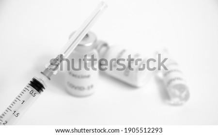 Selective focus on syringe on blurred background of ampoules with vaccine COVID-19. Health protection. Black and white Coronavirus Vaccine with copy space. Vaccination against Sars-CoV-2.