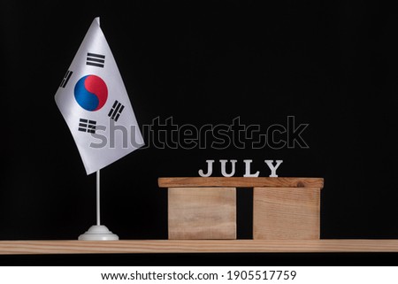 Wooden calendar of July with table South Korea flag on black background. Holidays of South Korea in July