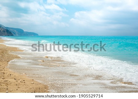 Beautiful sunny sea beach with amazing azure blue water and sky with fluffy clouds.