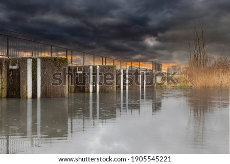 Sluice Gate On The River With Dramatic Clouds In Sky