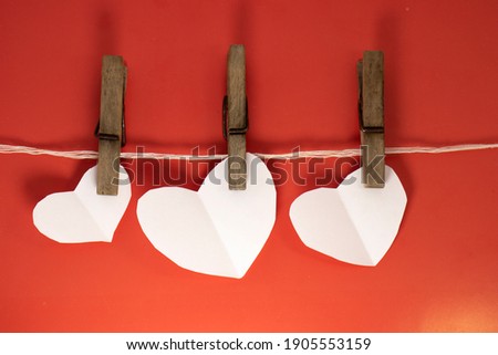 white valentines hanging on a rope with clothespins on a red background