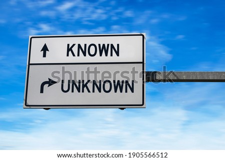 Road sign with words known and unknown. White two street signs with arrow on metal pole. Directional road, Crossroads Road Sign, Two Arrows on blue sky. Royalty-Free Stock Photo #1905566512