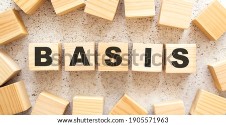 The word BASIS consists of wooden cubes with letters, top view on a light background. Work space.