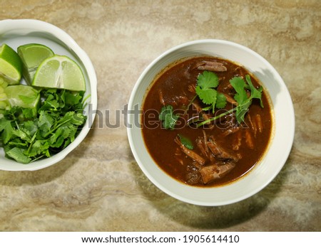 Birria in consomme and partial view of toppings.