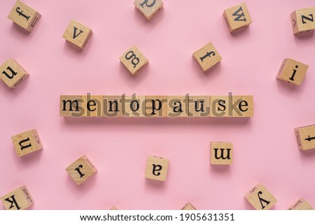 Menopause word on wooden block. Flat lay view on light pink background. Royalty-Free Stock Photo #1905631351