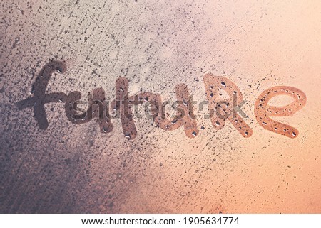 The word future on the window with water drops on sunny background. Fogged window calligraphy. Bright Future concept