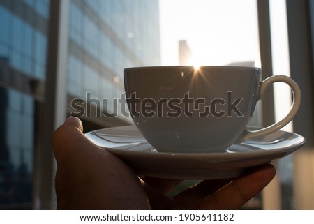 White cup of coffee over a cityscape blurred background