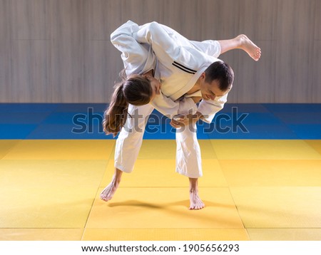 Adult male judoka throwing young female judo girl with hip throw Royalty-Free Stock Photo #1905656293