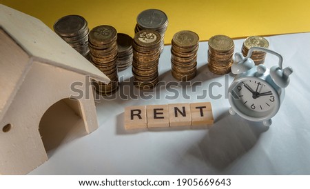 RENT wording on white table with house, coins and clock