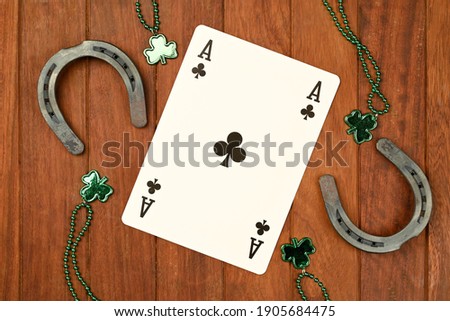 Concept of St. Patrick. Green clover necklaces and lucky horseshoes with poker cards on wooden background, top view for text
