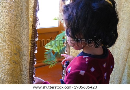 The girl is looking out the window at the street