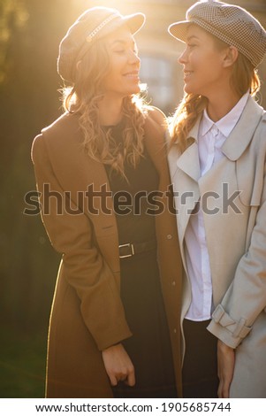 Two girls walking in city park and smilling. Autumn picture