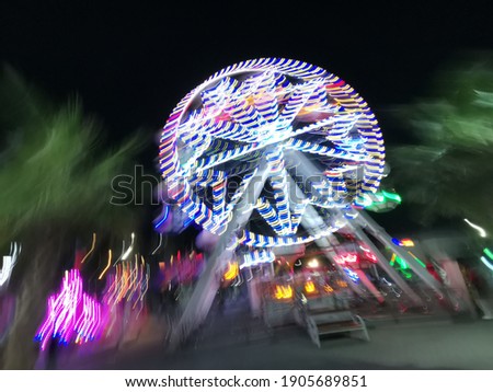 blurred motion from long exposure at night of Ferris wheel and a funfair