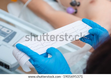 Heart cardiogram in the hands of a doctor close-up. Cardiologist is studying the testimony of an electrocardiograph. Royalty-Free Stock Photo #1905695371