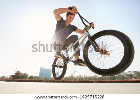 Street portrait of a bmx rider in a jump on the street in the background of the city landscape