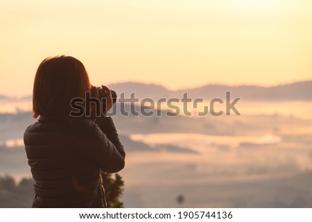 Asian female photographing misty landscape in morning spend vacation in Khao Kho hill Thailand
