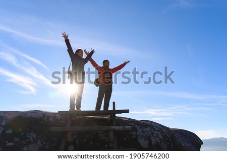 Father and daughter open arms enjoying the view of landscape after climb mountain peak