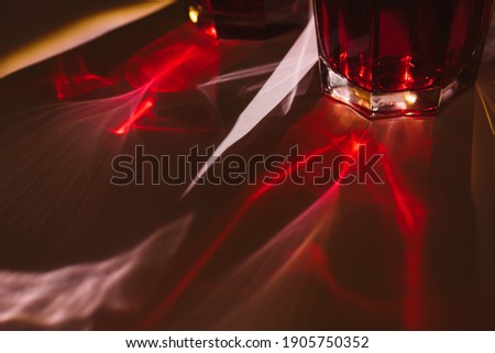 A ray of the sun shines through a glass of red water. Wine. Glare from the sun. Background for text