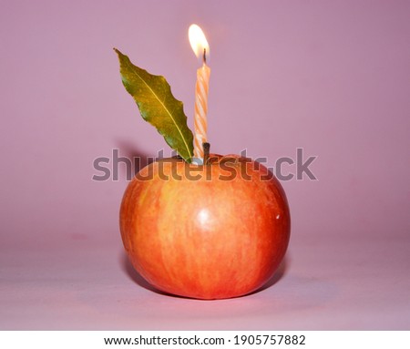 apple with a lighted candle, on pink background. Ideas for birthday party.Pop art style