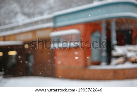 The building is out of focus. Retro old bar wood exterior in American Wild West style. Background for text or images. Snowing