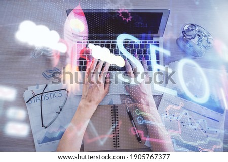 Double exposure of woman hands working on computer and SEO hologram drawing. Top View. Search optimization concept.