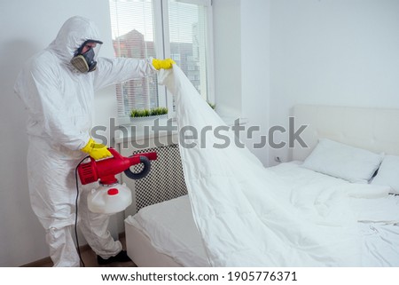 pest control worker lying on floor and spraying pesticides in bedroom