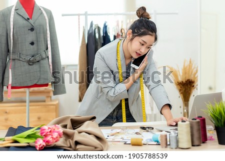 Asian young women fashion designer using laptop working and received order customer for design tailor and cloth in the showroom,  Lifestyle Stylish tailor taking measurements on.  Business SME 