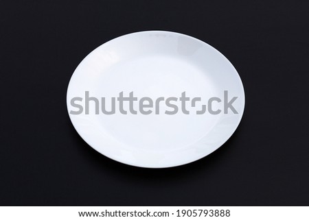 Empty white dish plate on dark background. Copy space