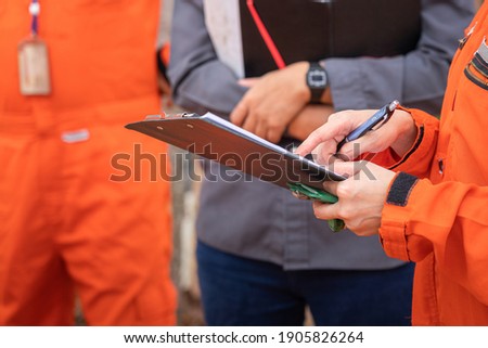 Action of safety audit and inspection team is making a discussion on the paperwork with colleague. Close-up and selective focus at personal 's hand. Royalty-Free Stock Photo #1905826264