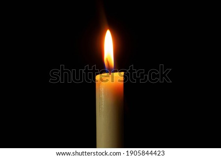 Candle light burning brightly in the black background.
