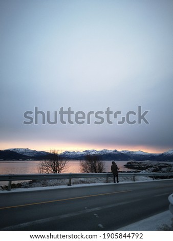 View of a guy capturing sunset picture at Atlantic Ocean Road, Norway.