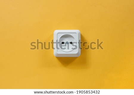 white electrical outlet in the middle of a yellow wall close-up