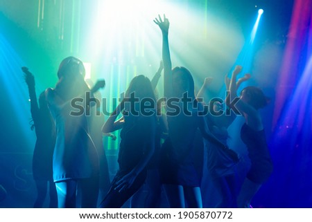 Silhouette image of people dance in disco night club to music from DJ on stage . New year night party and nightlife concept . Royalty-Free Stock Photo #1905870772