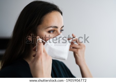 Woman Putting On Medical N95 Face Mask Royalty-Free Stock Photo #1905906772