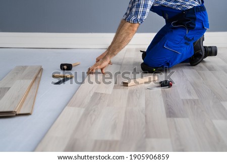 Hardwood Floor Renovation. Construction Worker Doing New Laminate Installation Royalty-Free Stock Photo #1905906859