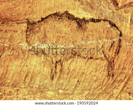 Abstract children art in sandstone cave. Black carbon paint of bison on sandstone wall, copy of prehistoric picture.