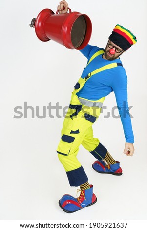 Holiday and fun concept. The clown fireman holds a fire barrel in his hands in front of his face.