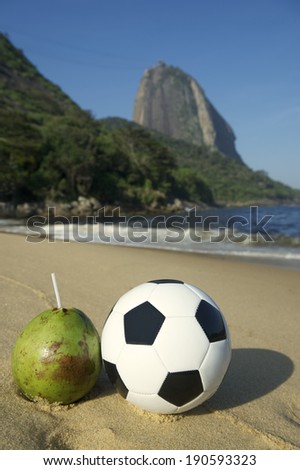Football soccer ball standing next to fresh green drinking coconut coco verde gelado Red Beach Sugarloaf Mountain Rio de Janeiro Brazil