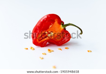 Isolated image of a habanero red chilli pepper cut in half with seeds around. Royalty-Free Stock Photo #1905948658